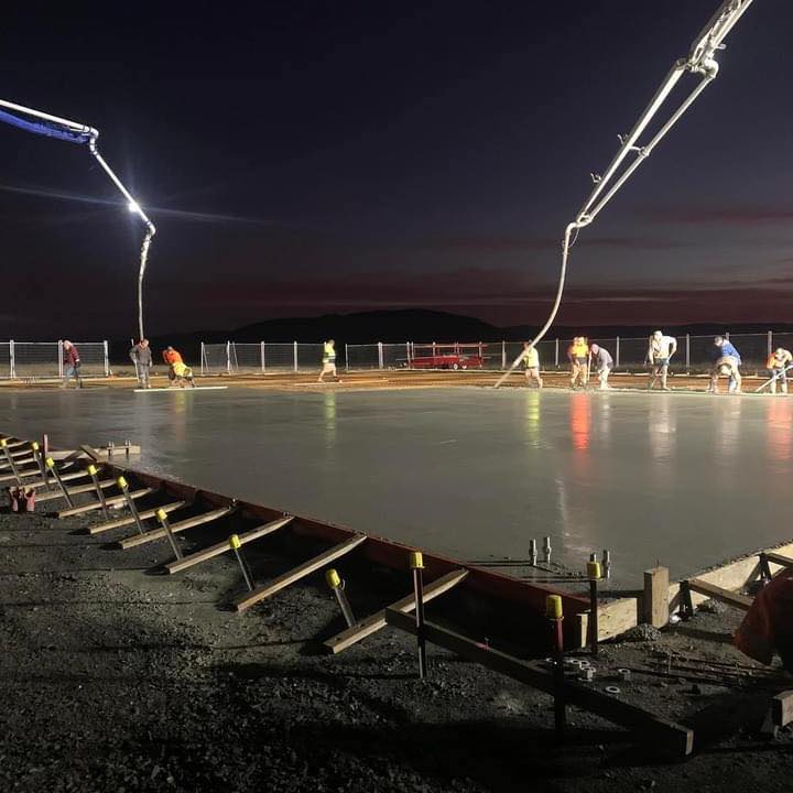 Night concrete pour with two boom arms and crew of six working a large lit slab, Southern Tasmania
